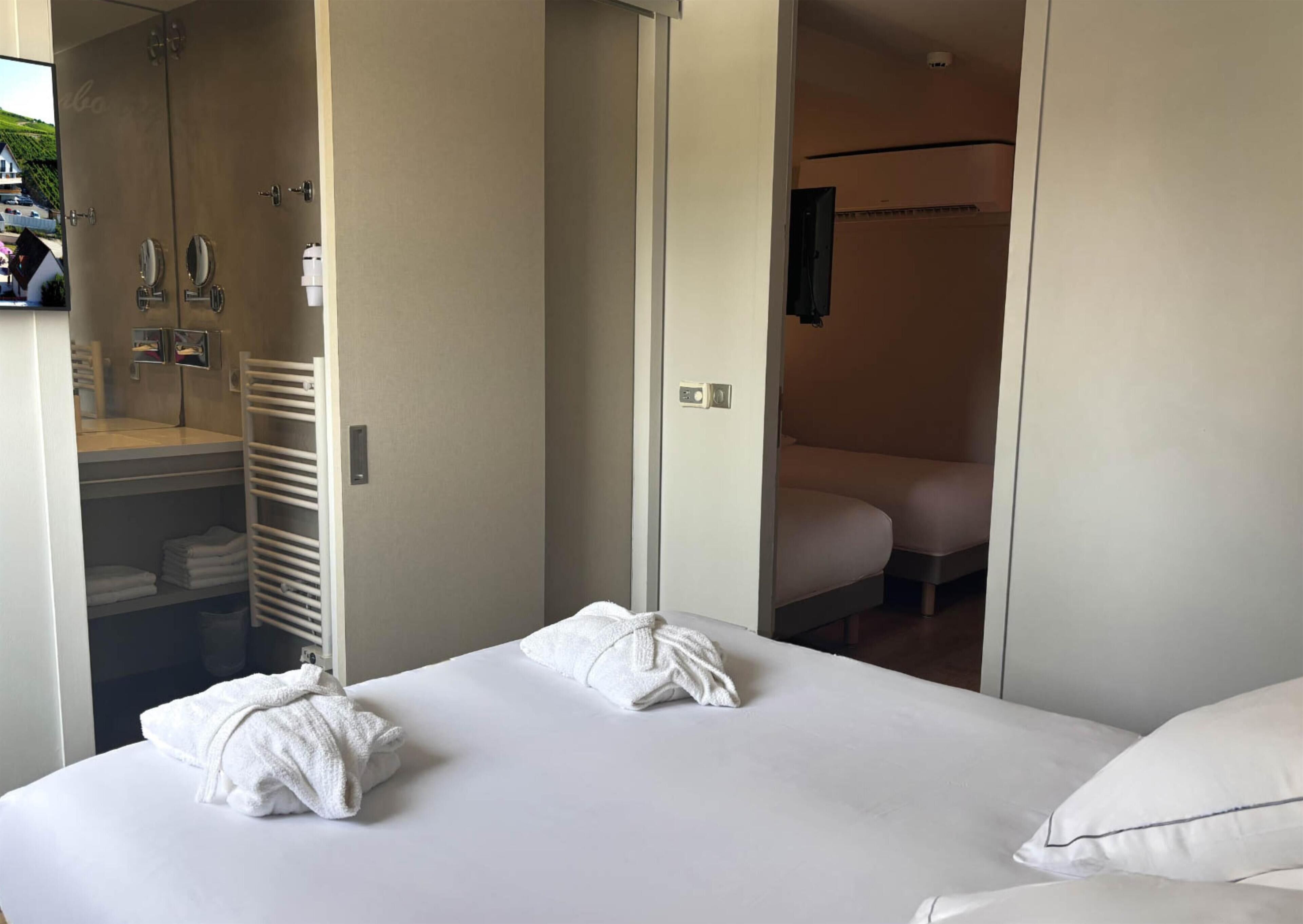 Ein Hotelzimmer mit einem Bett, einem Badezimmer mit Dusche und einem Schrank mit gefalteten Handtüchern.