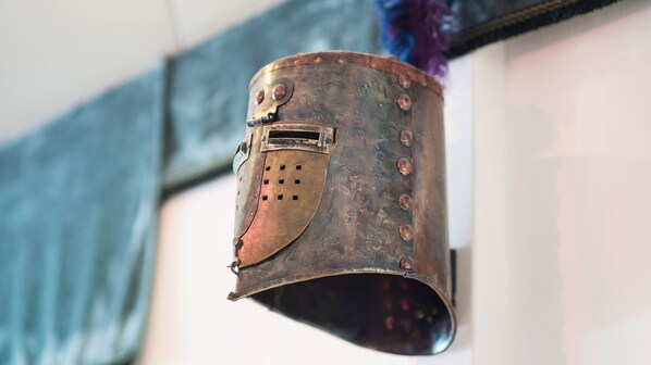Un casco metálico con visor colgado en una pared.
