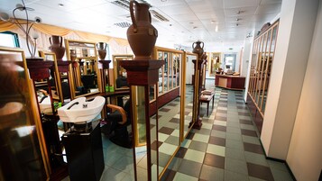 Een kapsalon interieur met spiegels, een wastafel en een zwart-witte vloer.