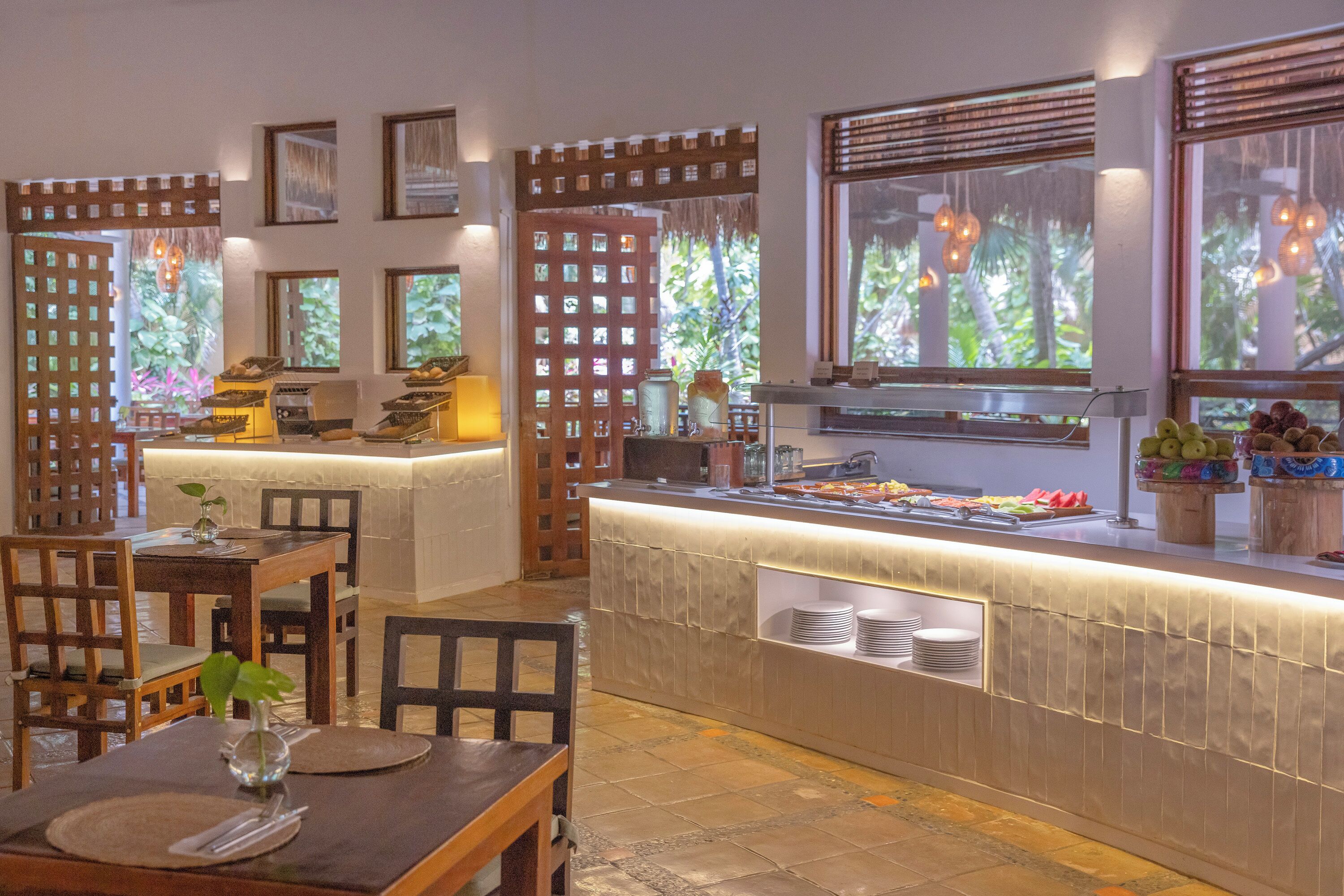 A restaurant with a buffet, wooden furniture, and large windows with natural light.