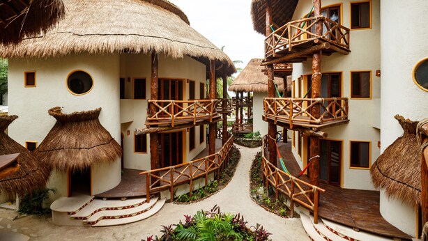 A resort with thatched-roof buildings, wooden balconies, and a central pathway. - Villas HM Paraiso del Mar (Isla Holbox)