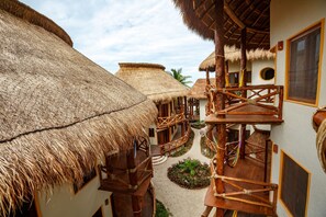 Un bâtiment traditionnel à toit de chaume, doté de balcons en bois et d’un jardin central.