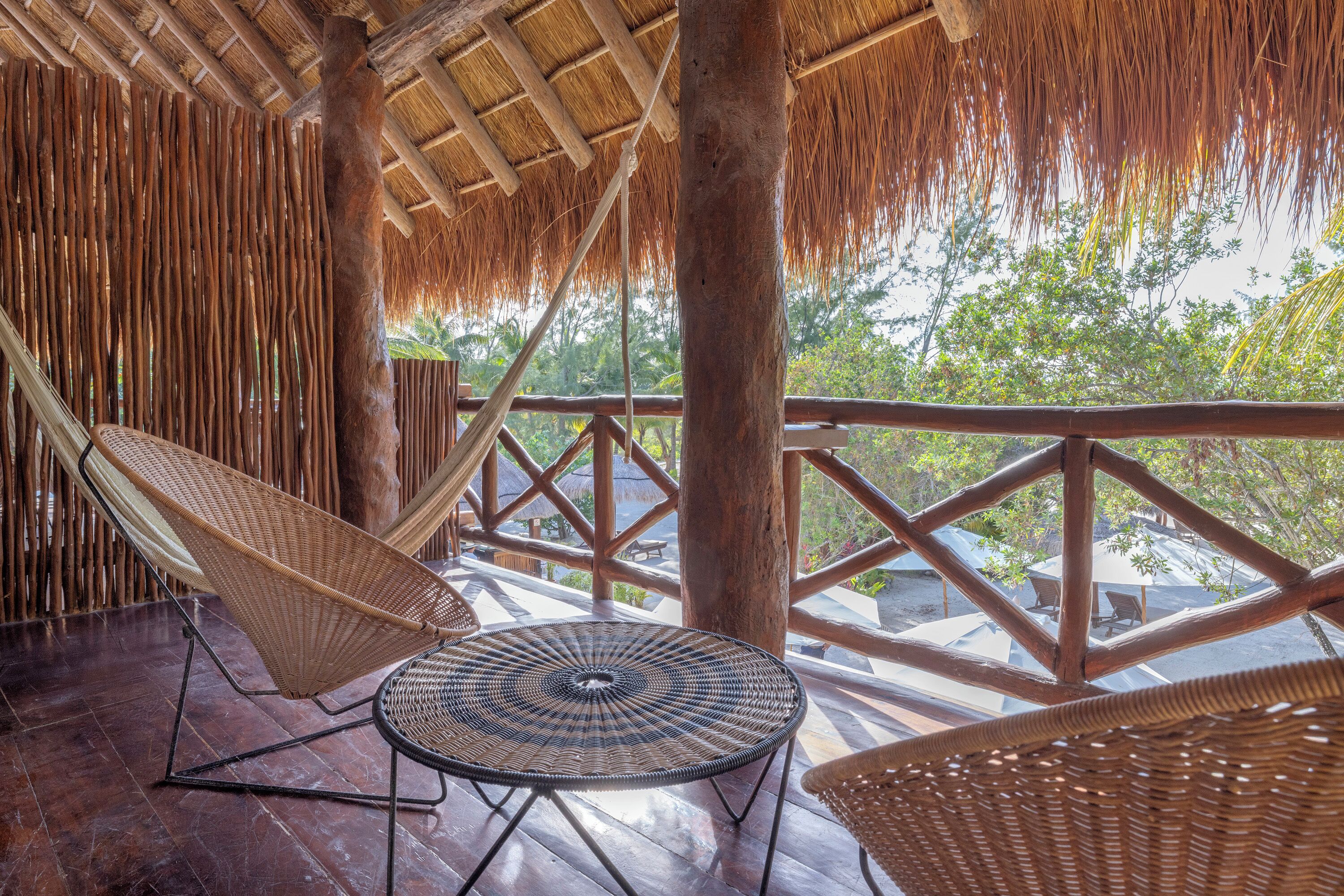 A covered outdoor area with wooden furniture and a thatched roof.