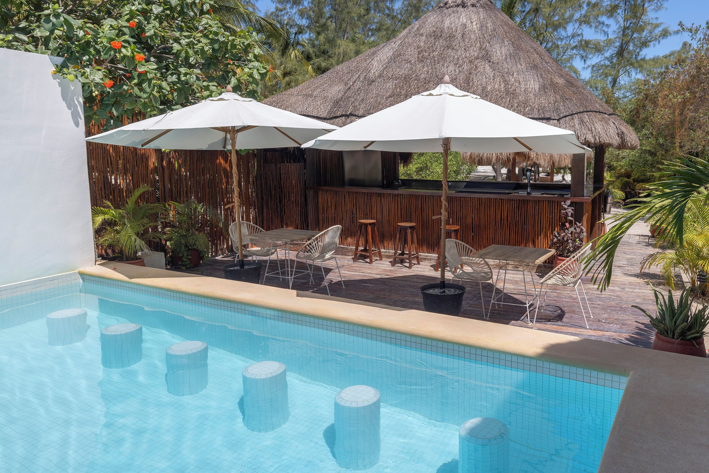 A pool area with a bar, umbrellas, and lounge chairs.