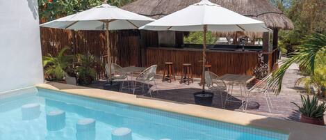 A pool area with a bar, umbrellas, and lounge chairs.