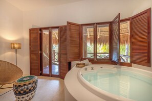 A room with a large bathtub, wooden shutters, a wicker chair, and a thatched roof visible through the windows. - Villas HM Paraiso del Mar (Isla Holbox)