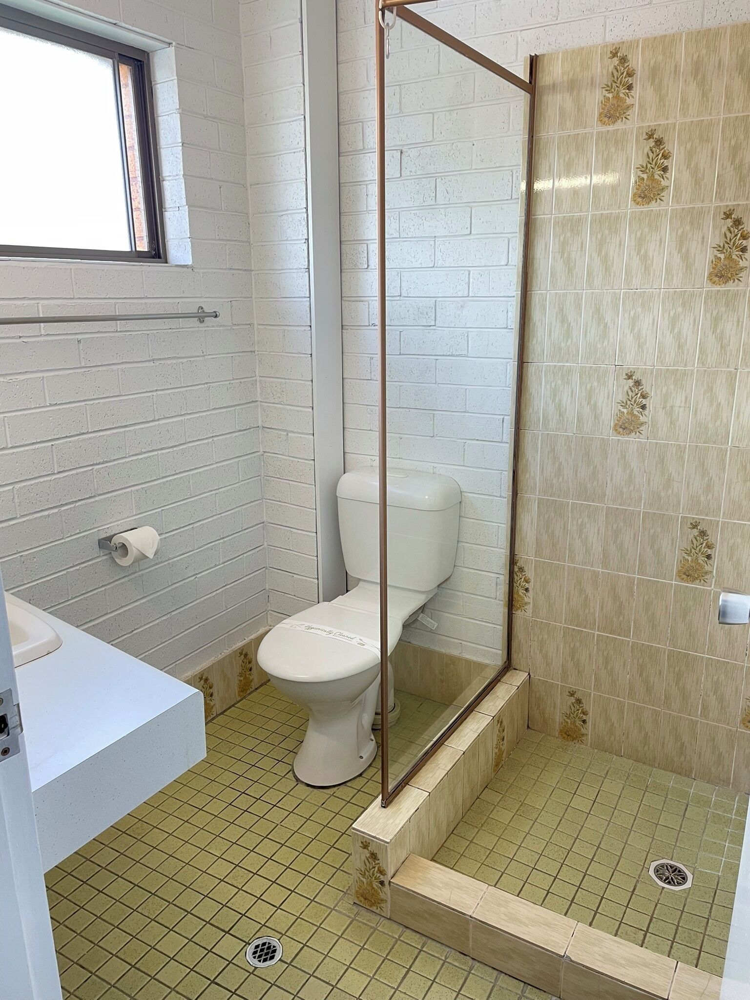 A small, clean bathroom with a toilet, sink, and shower area.