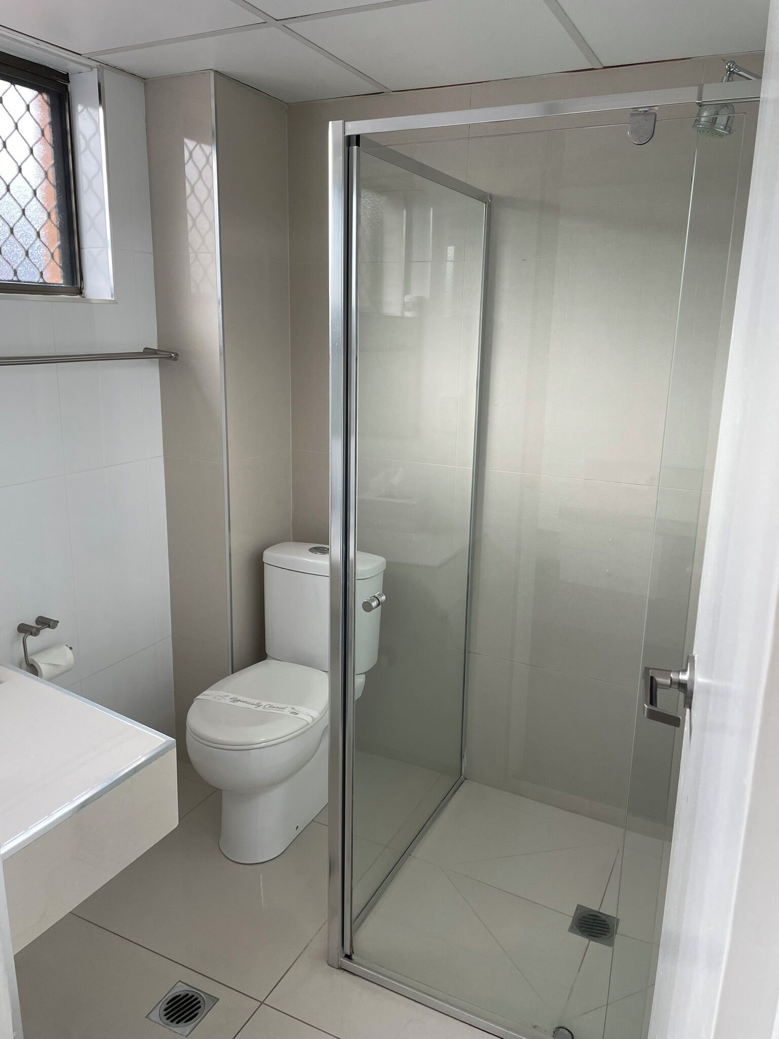 A modern bathroom with a glass-enclosed shower, a toilet, and a sink.