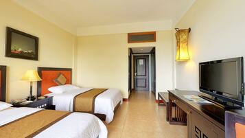 A hotel room with two beds, a TV, a desk, and a lamp.