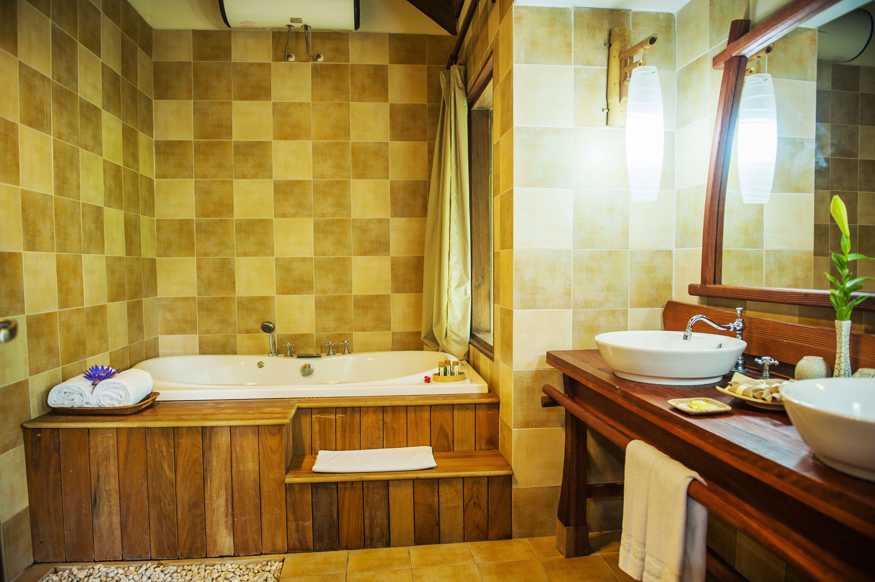 Un baño con una bañera de madera, un lavamanos y un espejo.