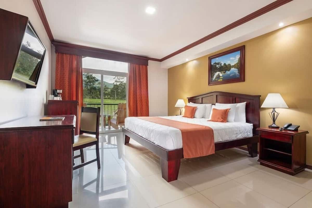 Habitación de hotel con cama, escritorio, silla y vistas al exterior.
