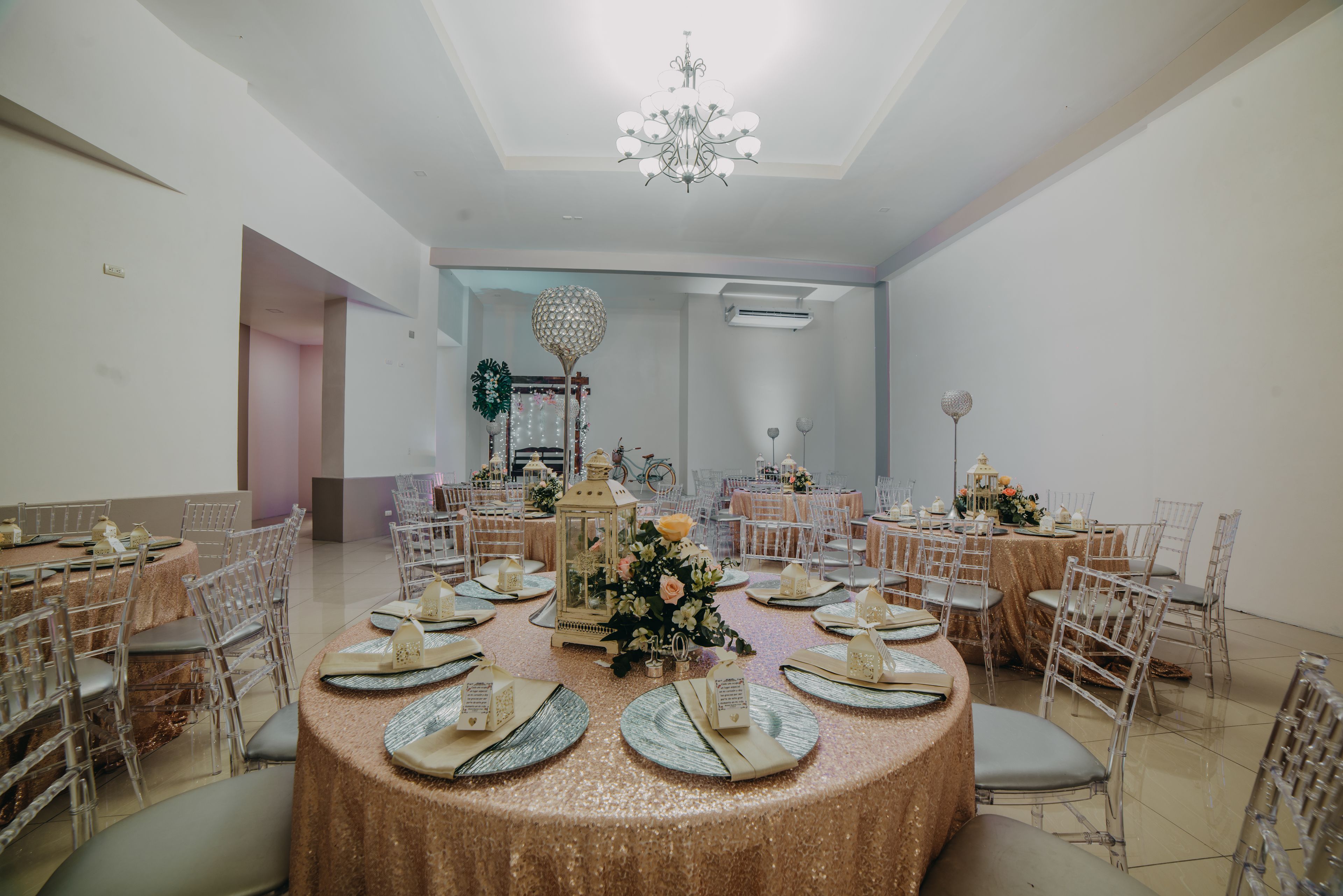 A banquet hall with round tables, chairs, and a chandelier.