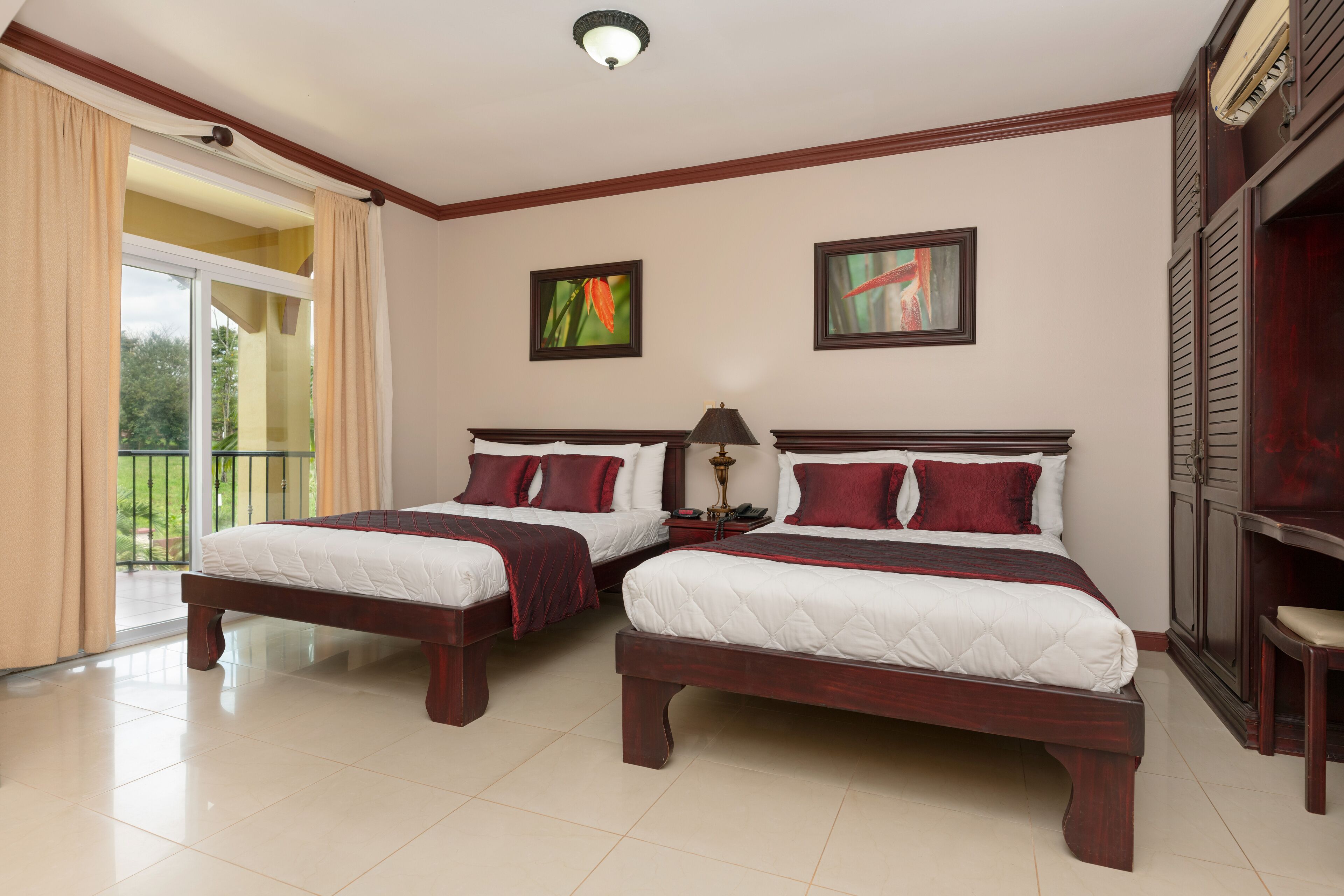A hotel room with two beds, a balcony, and artwork on the walls.