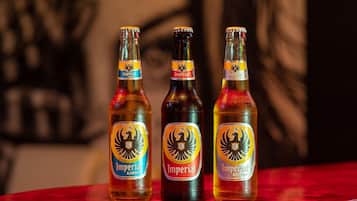 Tres botellas de cerveza con etiquetas sobre una mesa roja.
