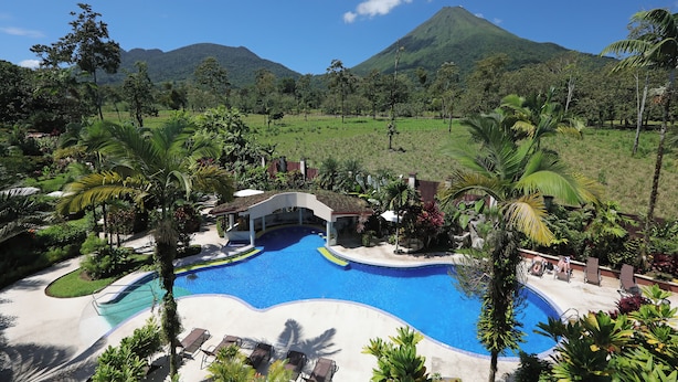 A resort with a swimming pool, lounge chairs, and tropical landscaping. - Hotel Magic Mountain SPA & Conference center (La Fortuna)