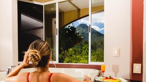 A woman in a red bikini sitting by a window with a mountain view. - Hotel Magic Mountain SPA & Conference center (La Fortuna)