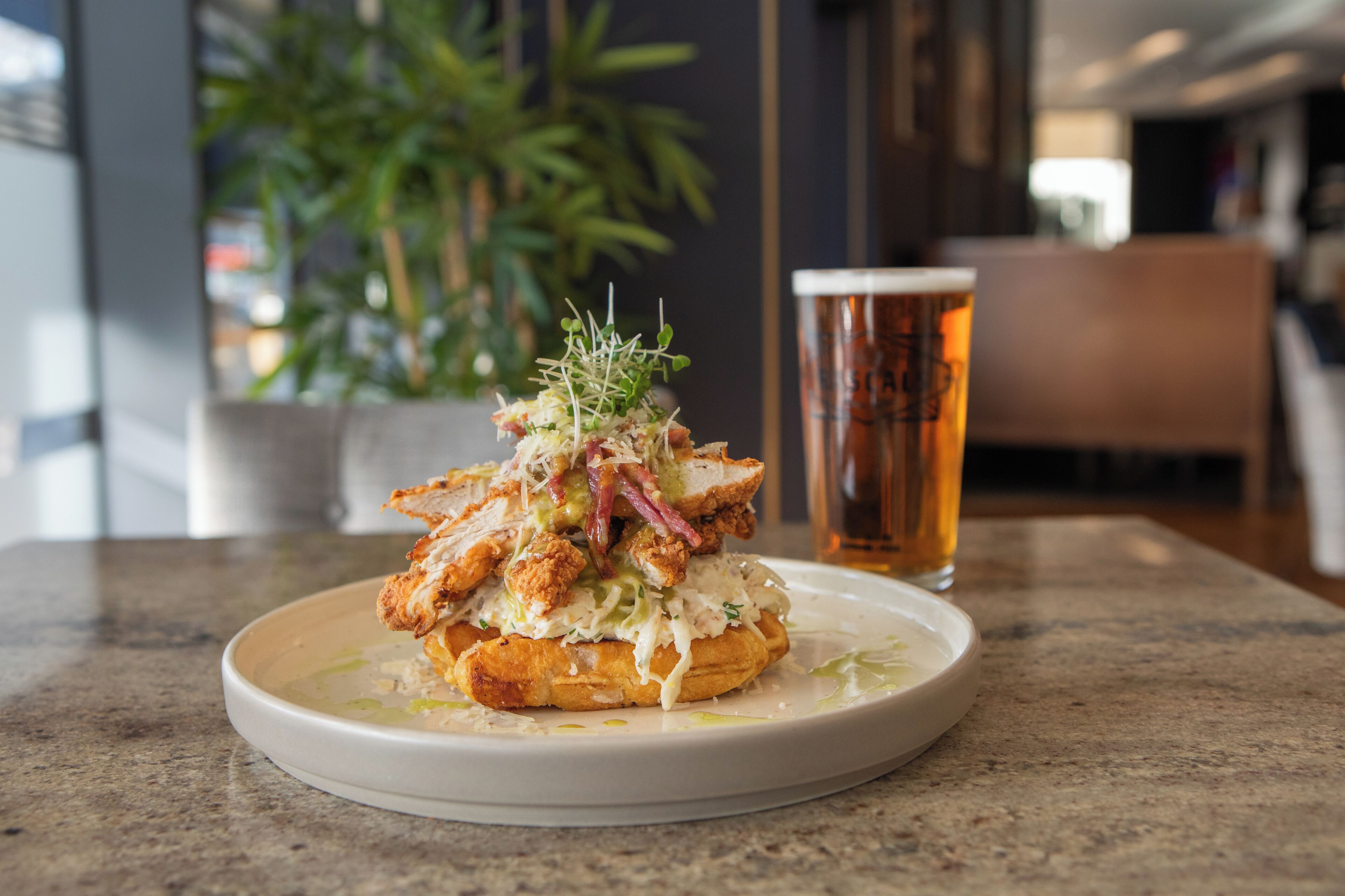 A plate of food with a glass of beer on a table.
