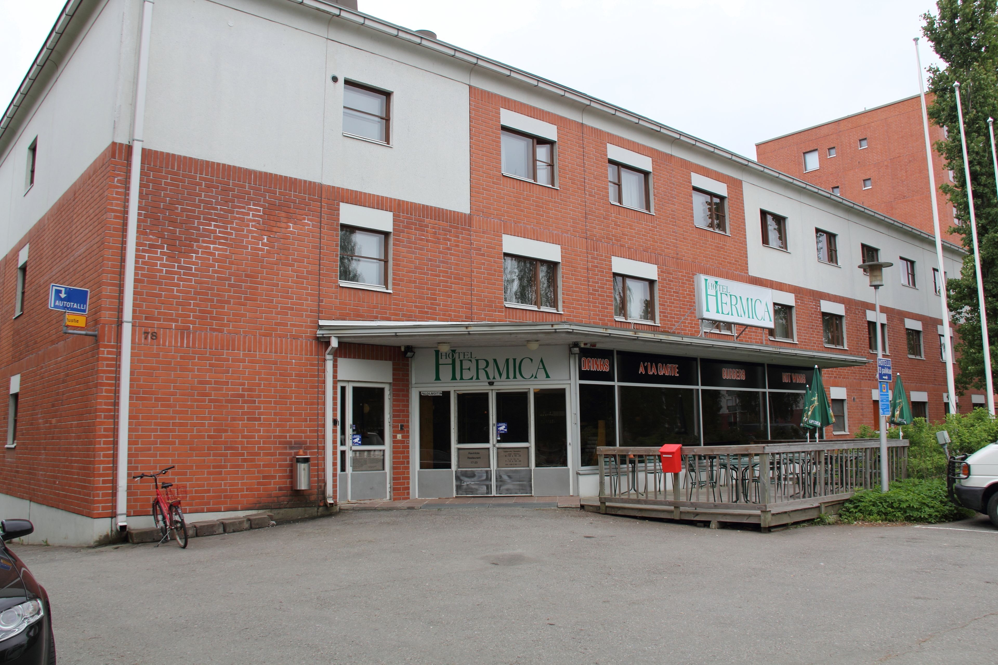 A hotel with a red brick facade, a covered entrance, and outdoor seating.