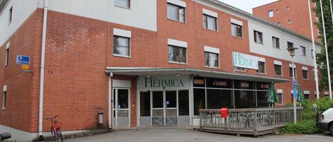 A hotel with a red brick facade, a covered entrance, and outdoor seating.