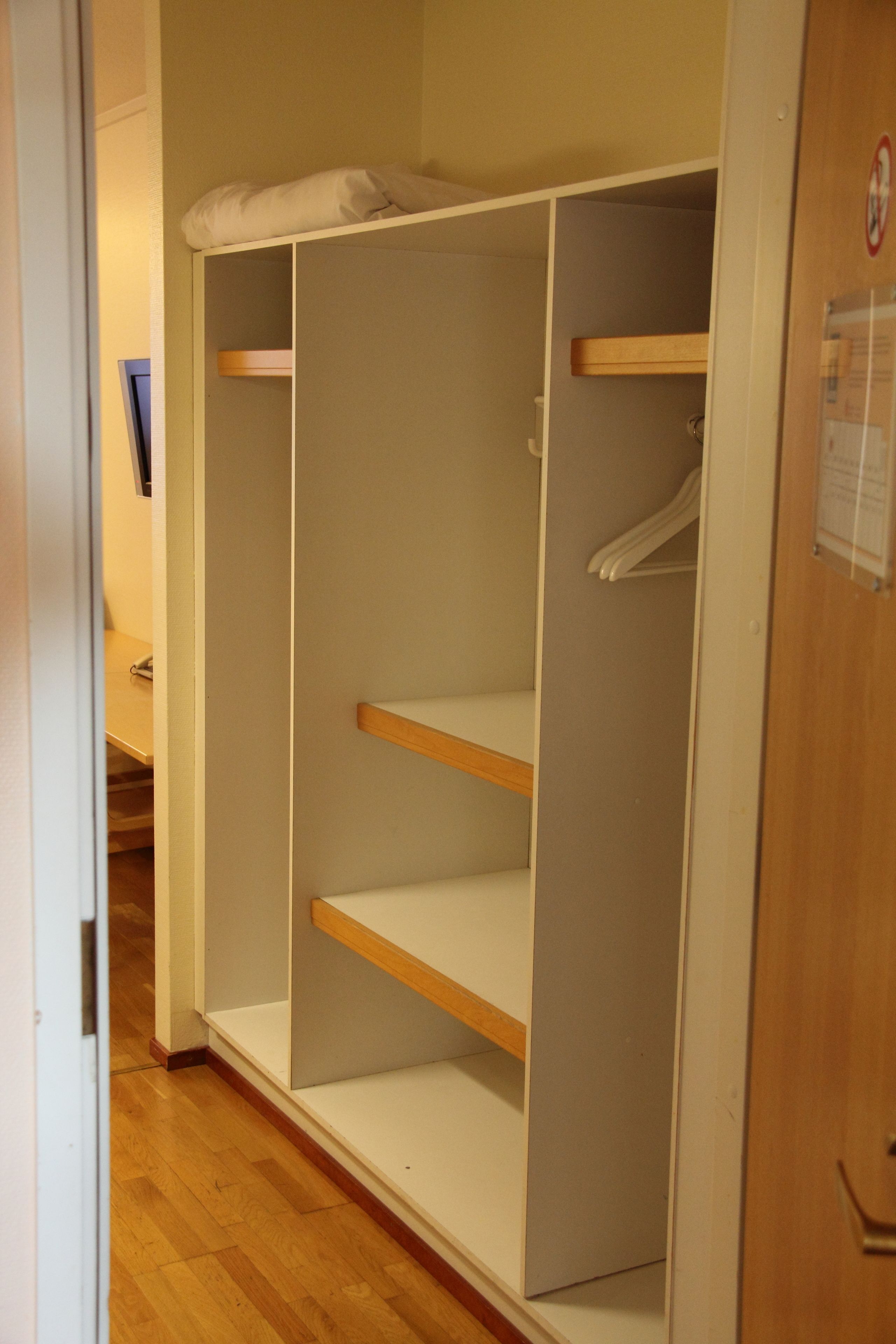 Ein begehbarer Kleiderschrank mit offenen Regalen und einer Kleiderstange.
