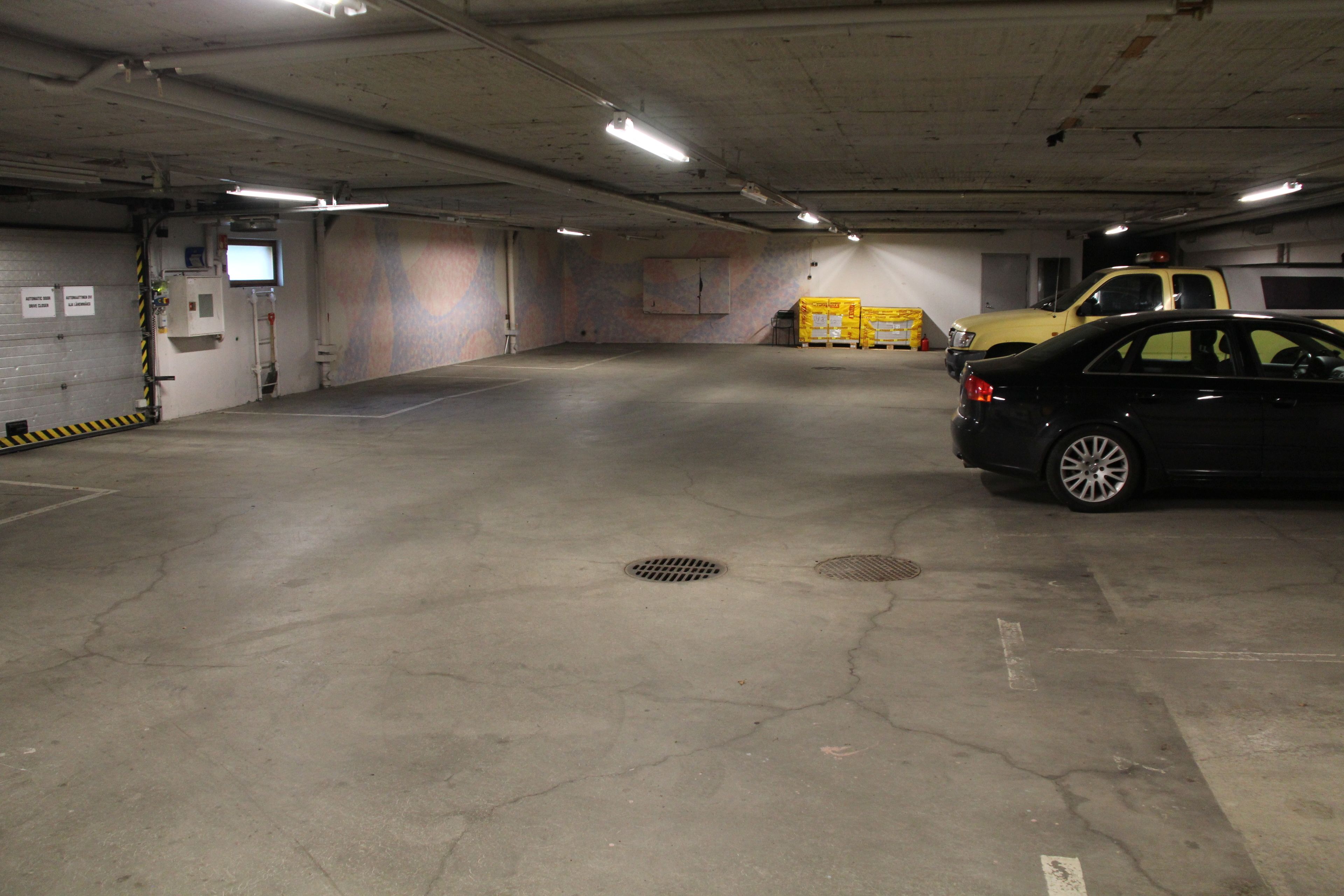 Eine Parkgarage mit Betonböden, einem gelben Lastwagen und einem schwarzen Auto.