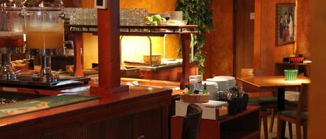 A bar area with a counter, stools, and a television mounted on the wall.