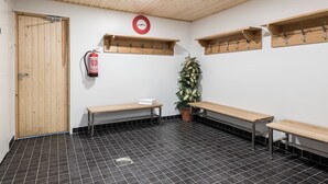 A public restroom with wooden benches, a fire extinguisher, and a clock on the wall. - Hotel Hermica (Tampere)