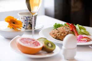Ein Tisch mit Speisen und Getränken, darunter eine Blume, ein Glas Champagner sowie Teller mit Obst und Gemüse.