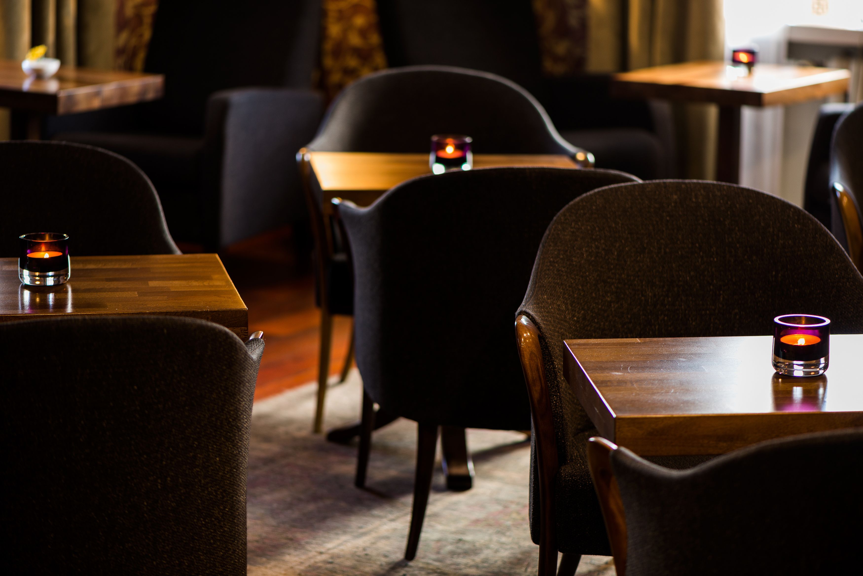 A dimly lit restaurant with wooden tables and dark chairs.
