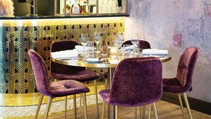 Ein Essbereich mit einem runden Tisch, violetten Samtstühlen und einer Chandelier.