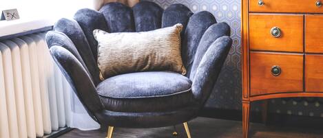 A dark blue armchair with a beige cushion, positioned next to a wooden dresser with multiple drawers.