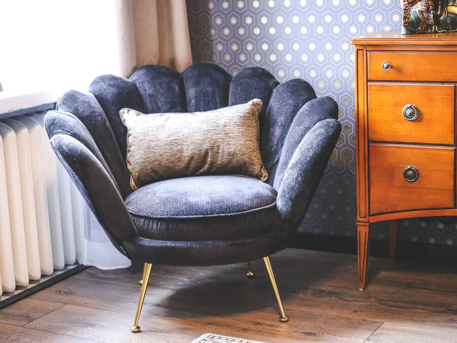A dark blue armchair with a beige cushion, positioned next to a wooden dresser with multiple drawers.