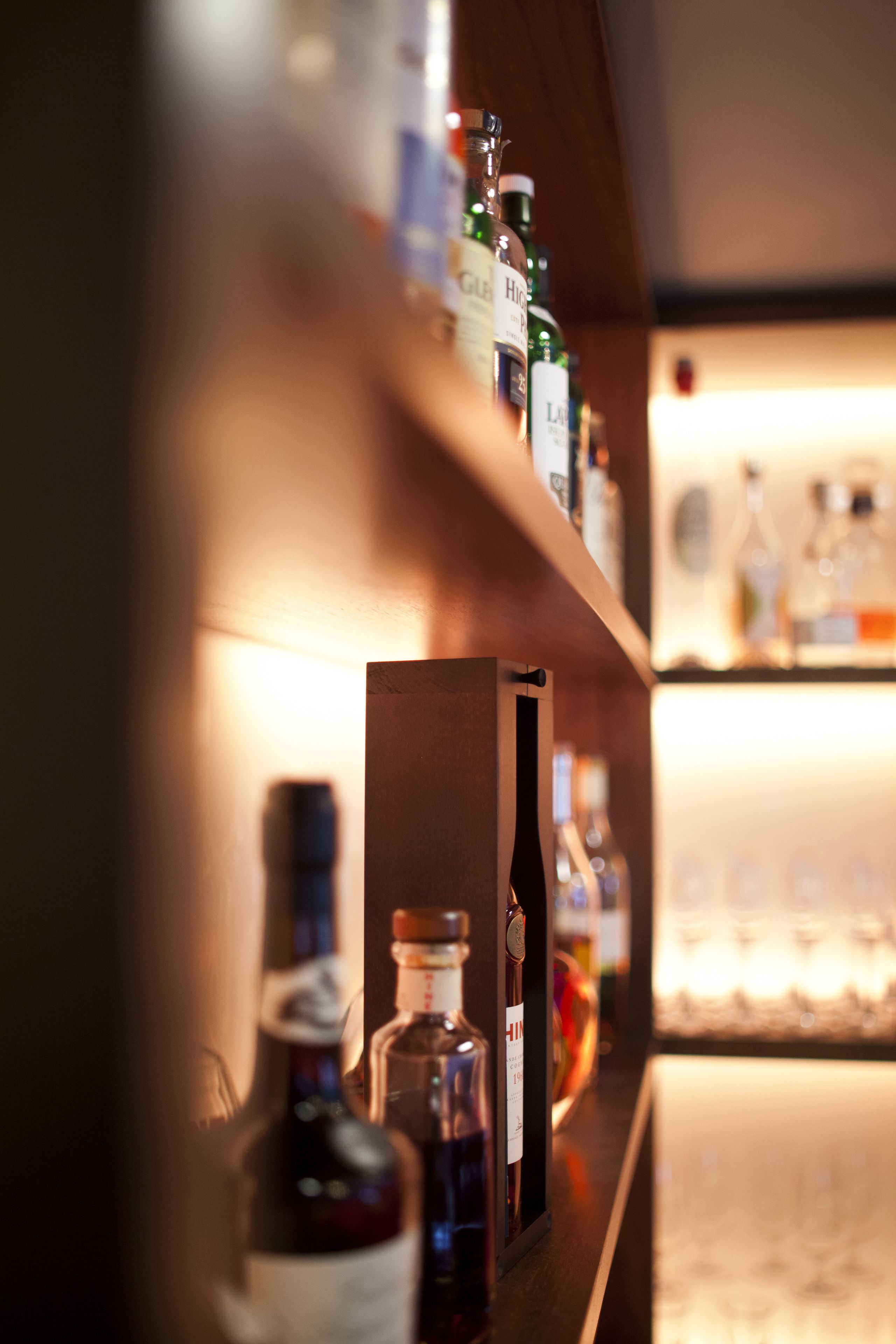A bar area with shelves of liquor bottles and glasses.