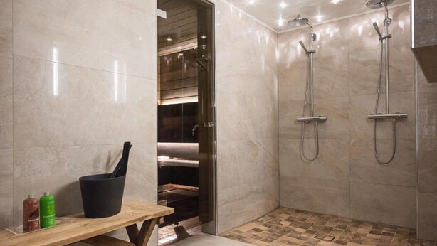 Ein modernes Badezimmer mit Dusche, einer Holzbank und einem Handtuchhalter.