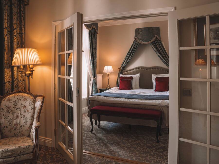 A room with a bed, a chair, and a lamp.