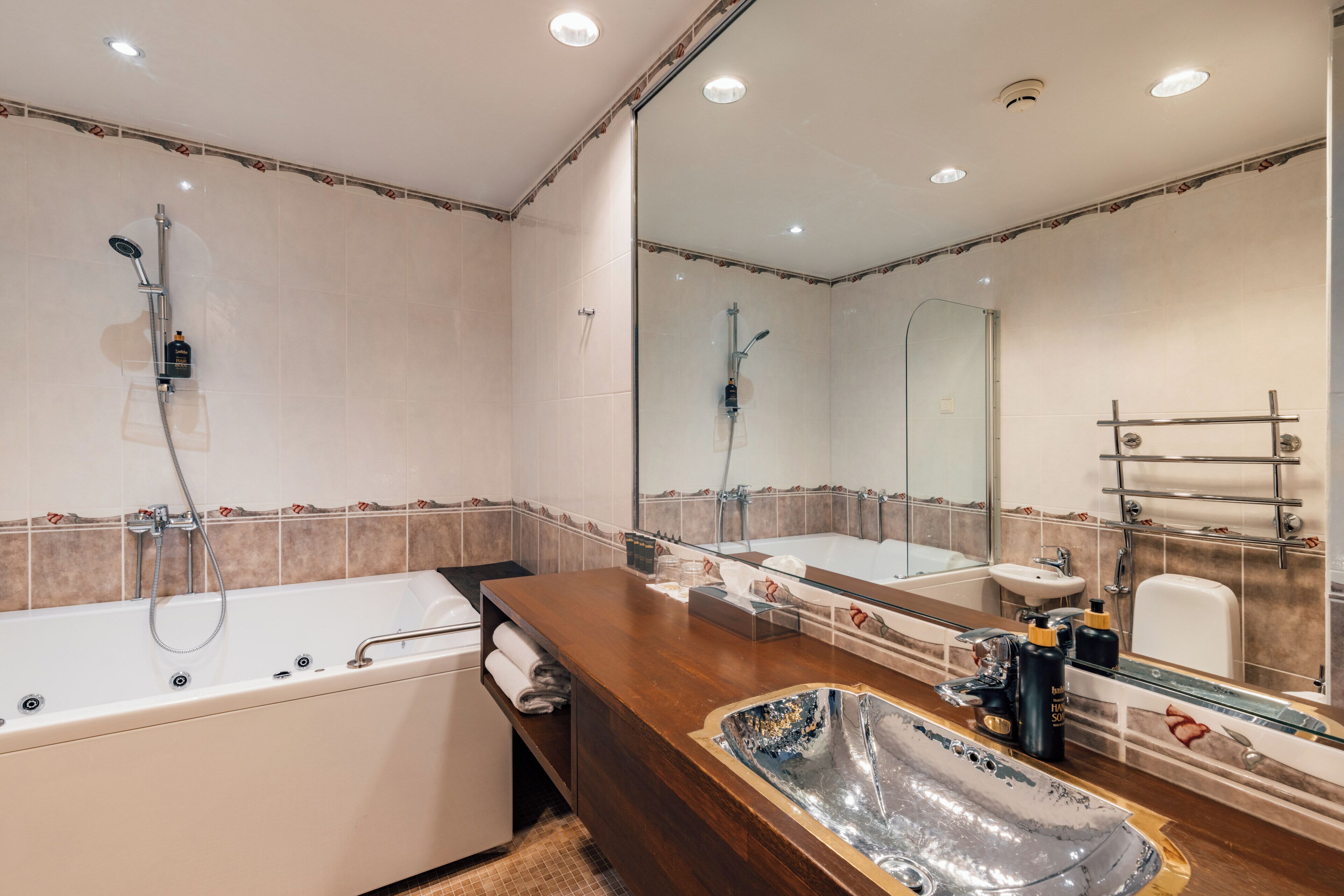 Une salle de bain moderne dotée d’une grande baignoire, d’une douche séparée et d’un meuble-lavabo avec un miroir.