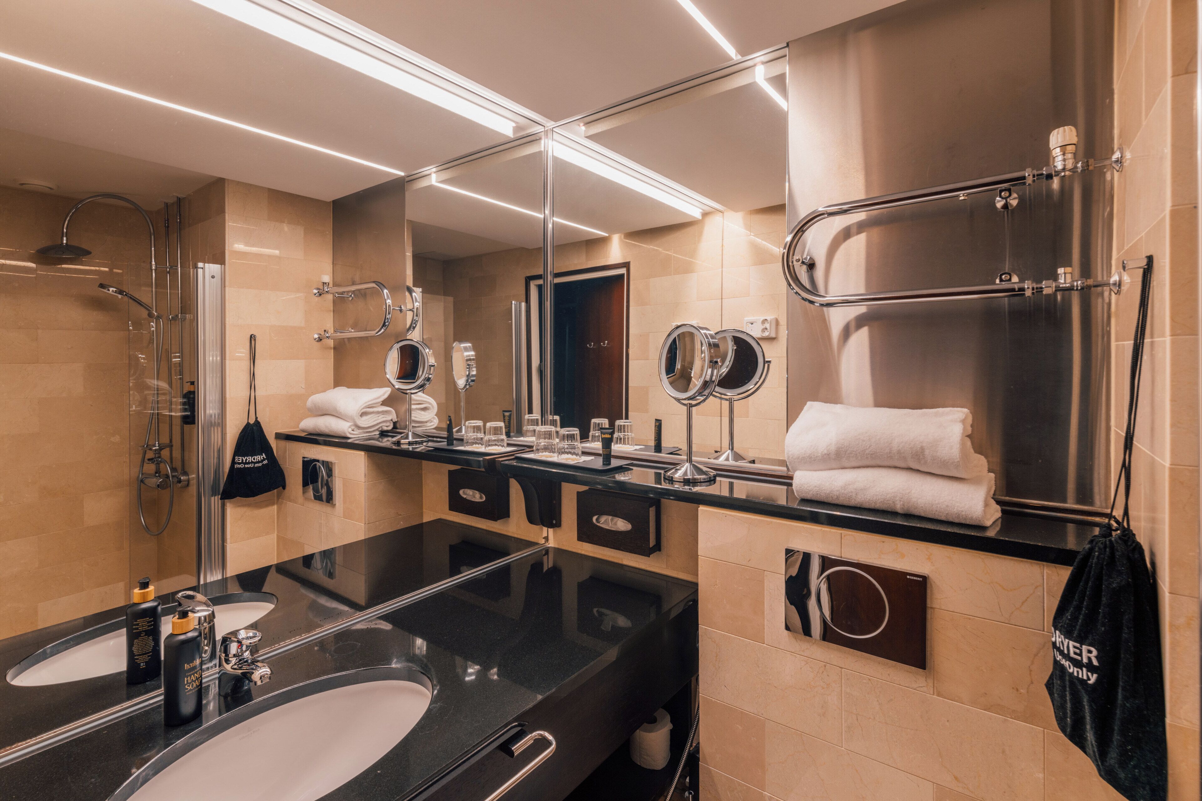 A modern bathroom with two sinks, a large mirror, and a shower area.