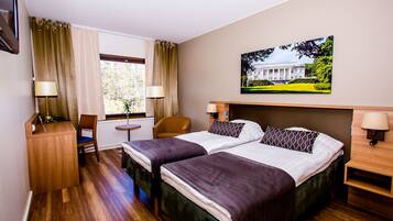A hotel room with two beds, a desk, a chair, a window with curtains, and a painting on the wall.