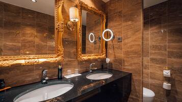 A bathroom with two sinks, a large ornate mirror, and a toilet.