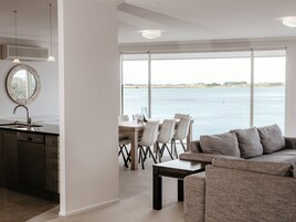 Una cocina moderna con un ventanal grande, una zona de comedor con vista al mar y un rincón de descanso acogedor.