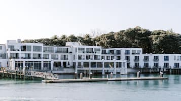 A waterfront hotel with multiple white buildings, a dock, and a bridge.
