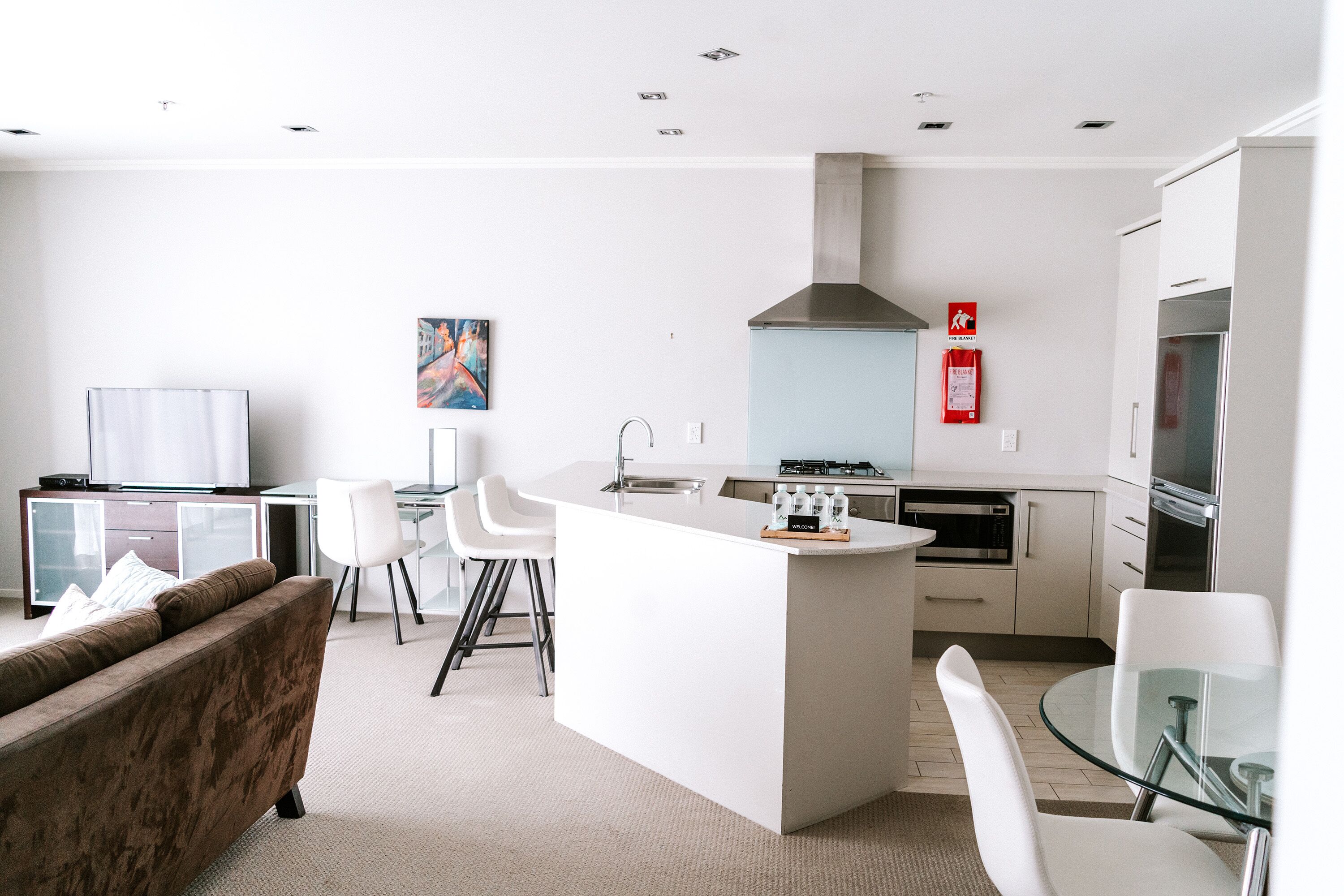 Una cocina moderna con una isla central, armarios blancos y una campana extractora de acero inoxidable.