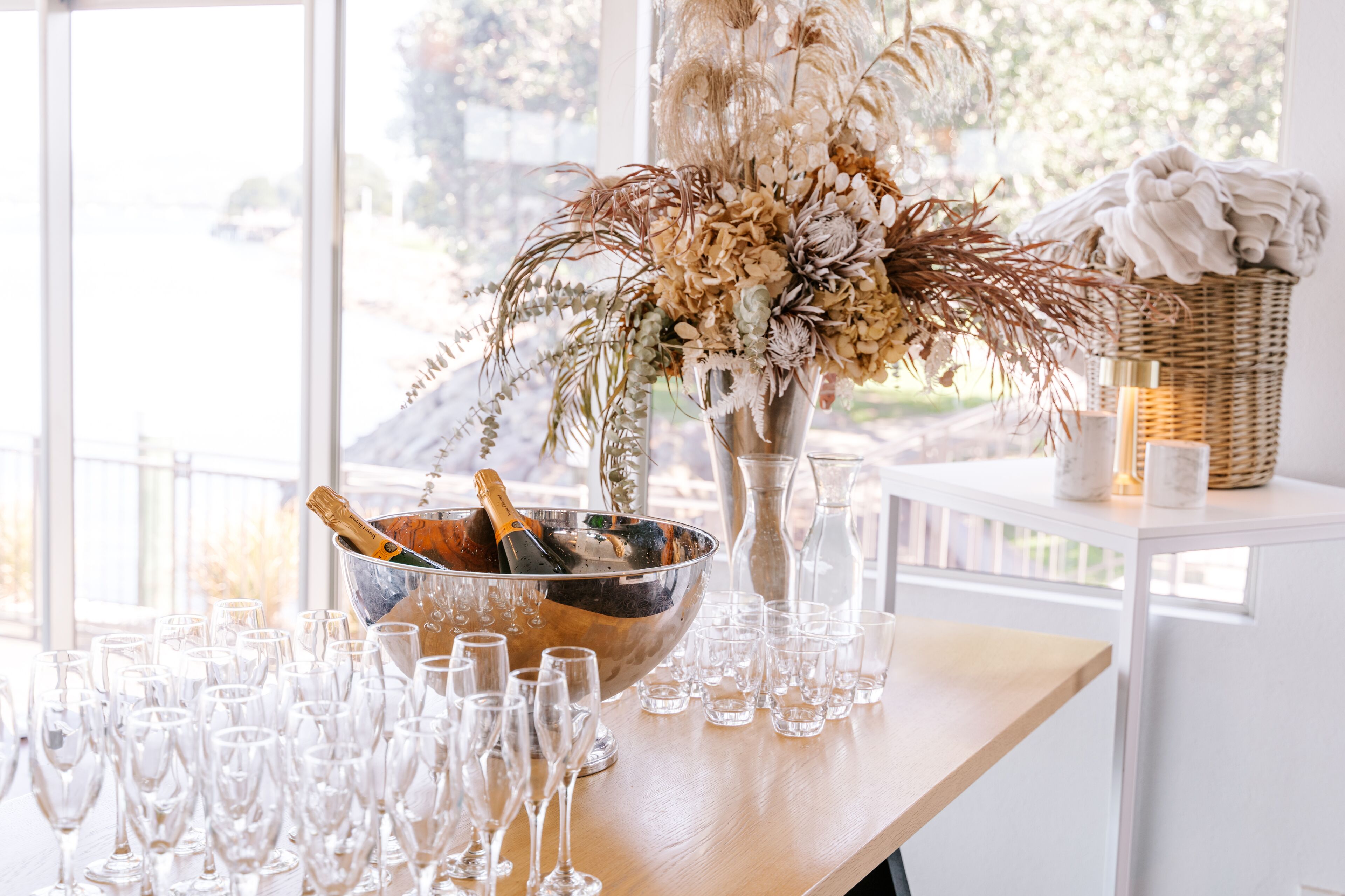 A table with a champagne bucket, glasses, and a floral arrangement.
