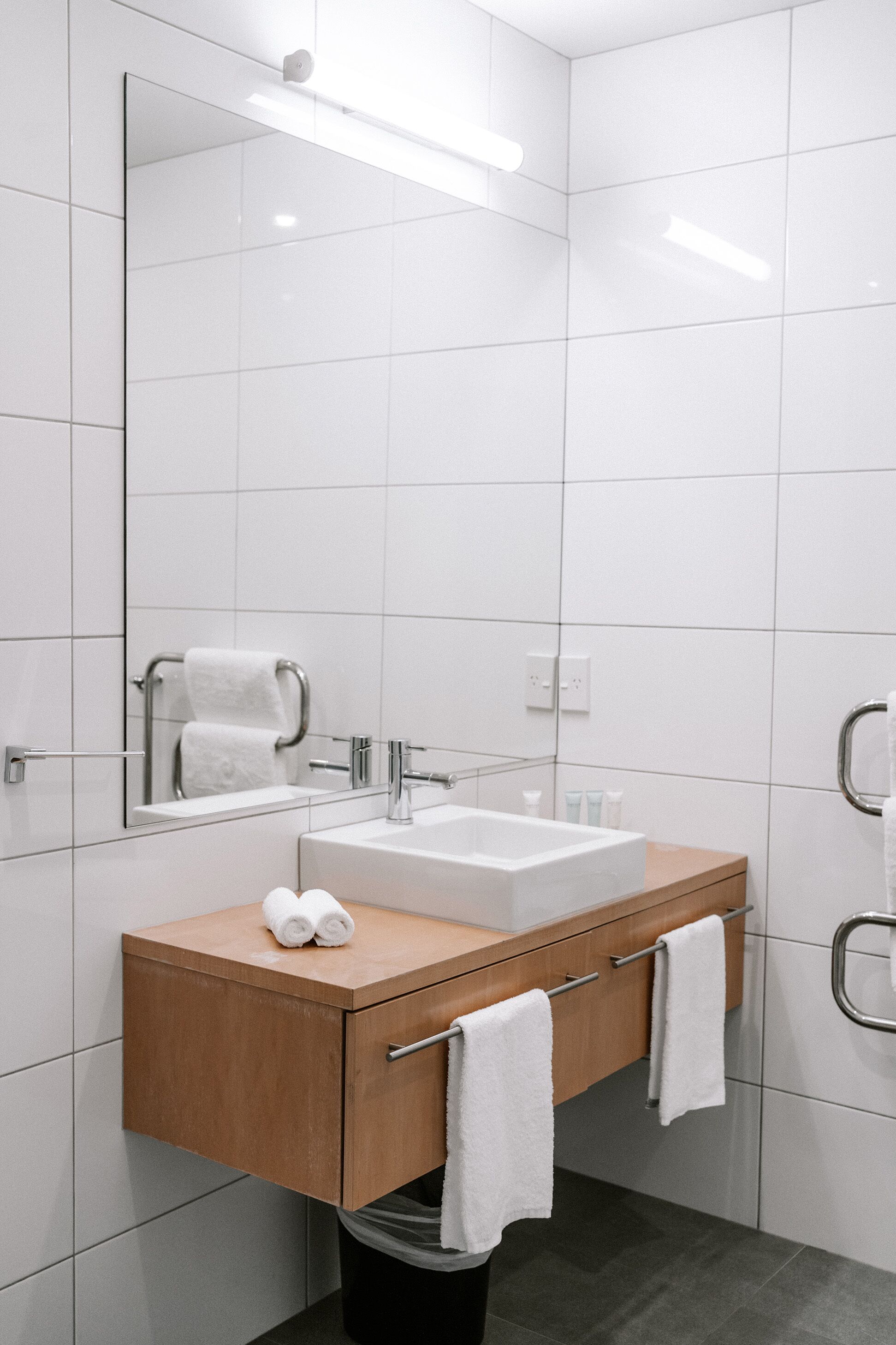 Une salle de bain moderne avec un lavabo blanc, un meuble-lavabo en bois et un miroir.