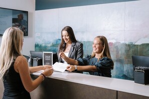 A reception desk with a modern design, featuring a digital screen and a framed menu board. - Trinity Wharf Tauranga (Tauranga)