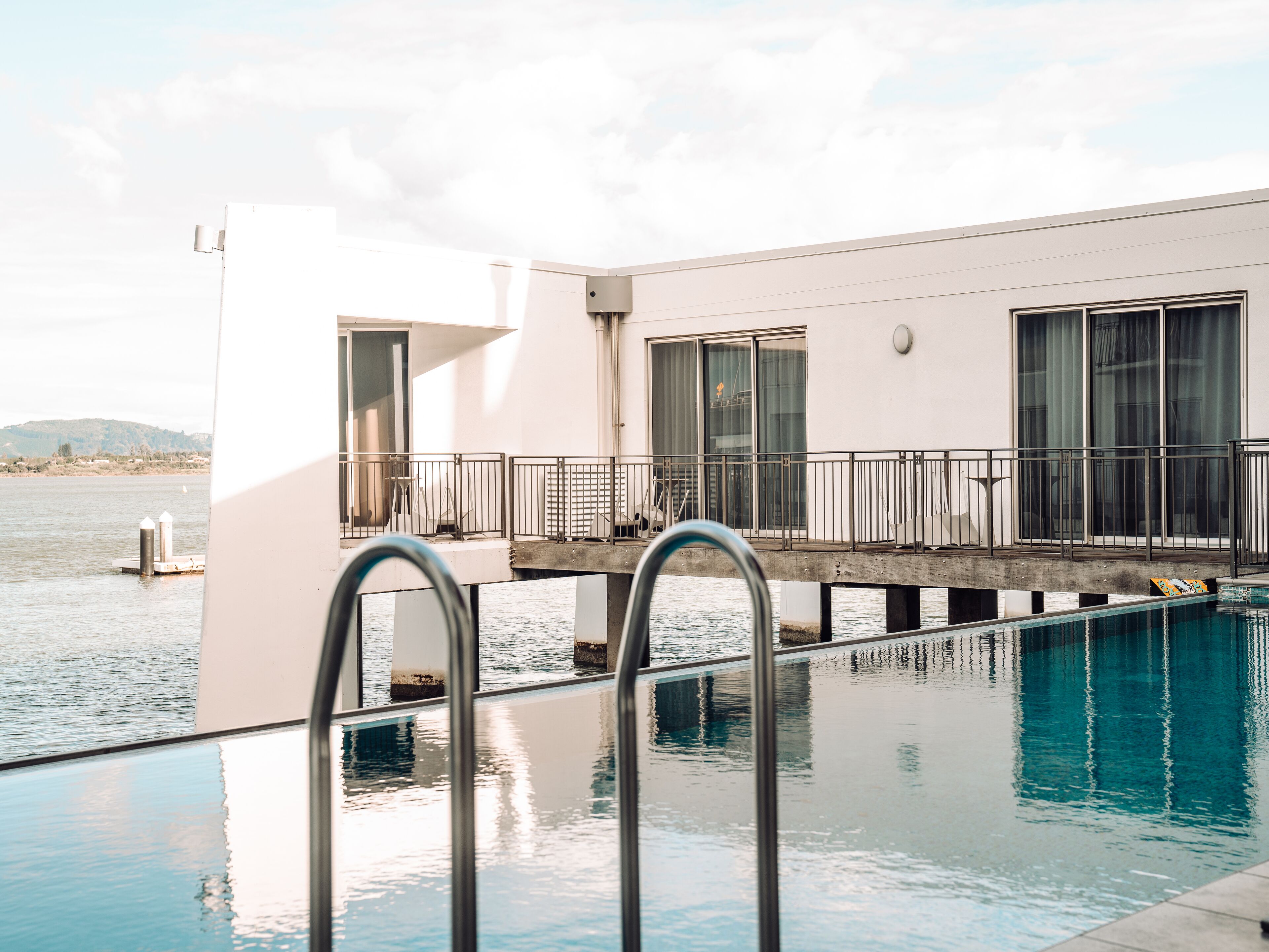 A modern building with a pool, a balcony, and a view of the water.