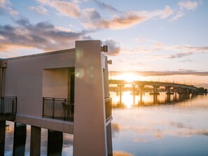 A modern building with a balcony, a bridge in the background, and a sunset over water. - Trinity Wharf Tauranga (Tauranga)