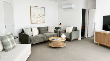 A modern living room with a grey sofa set, a coffee table, and a TV stand.