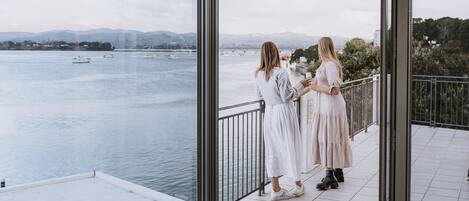 A balcony with a view of a body of water and distant mountains.