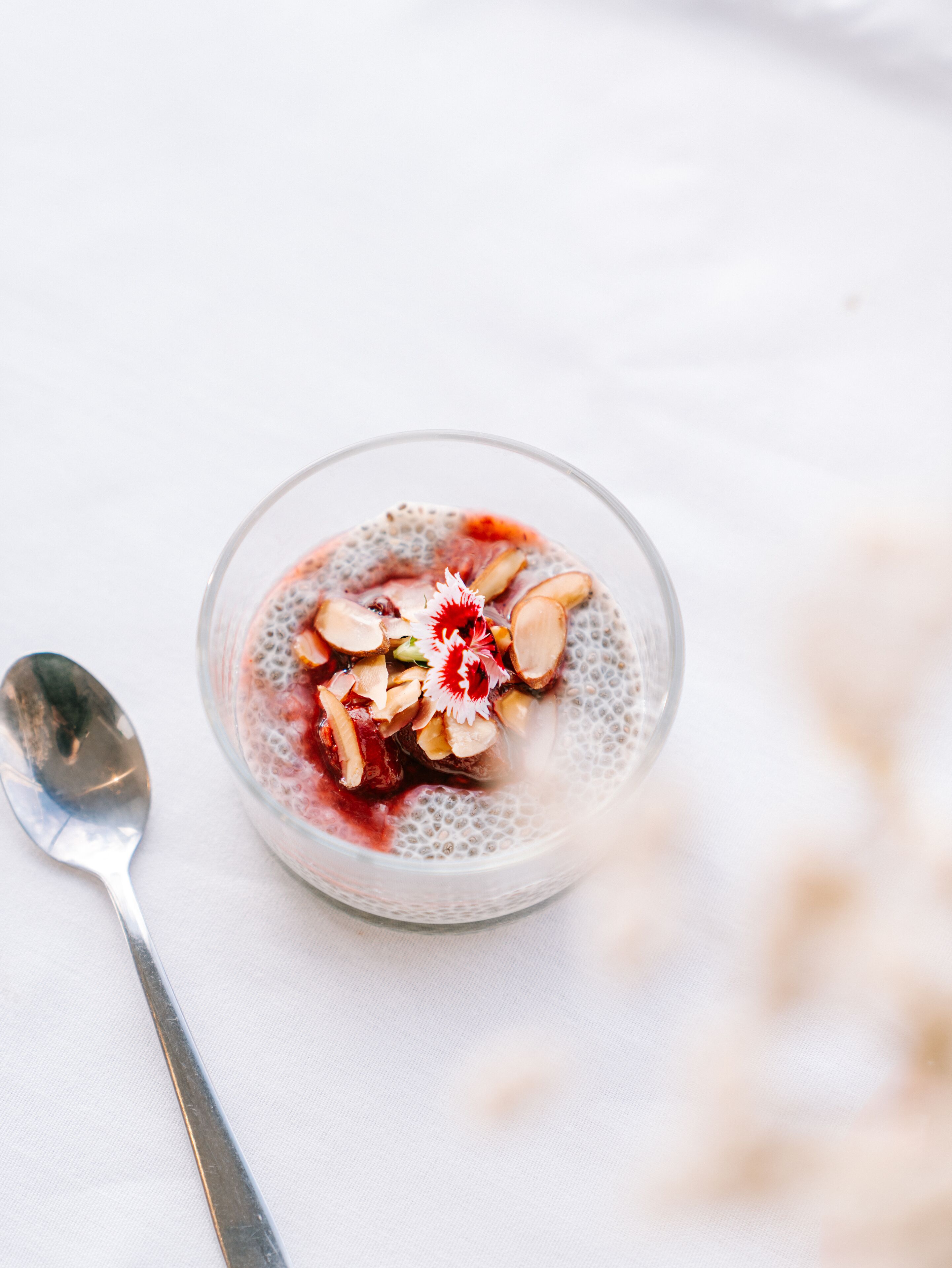 A bowl of dessert with a spoon beside it on a white surface.